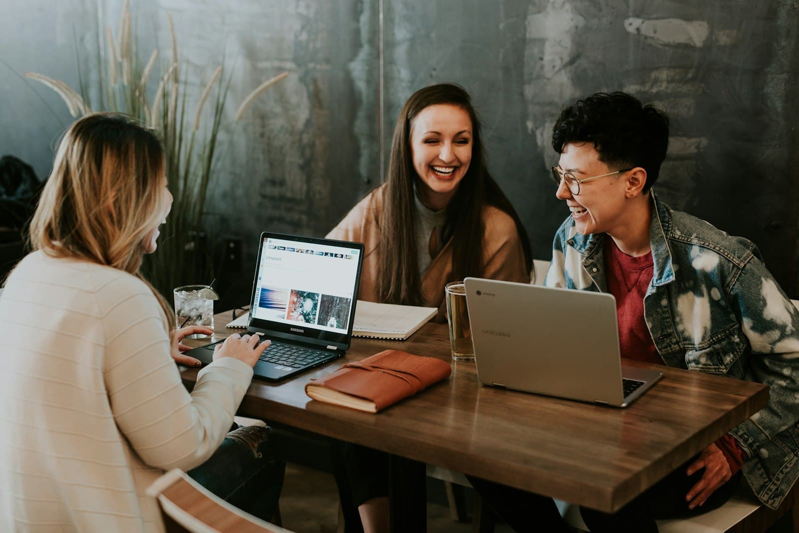A team laughing together around laptops